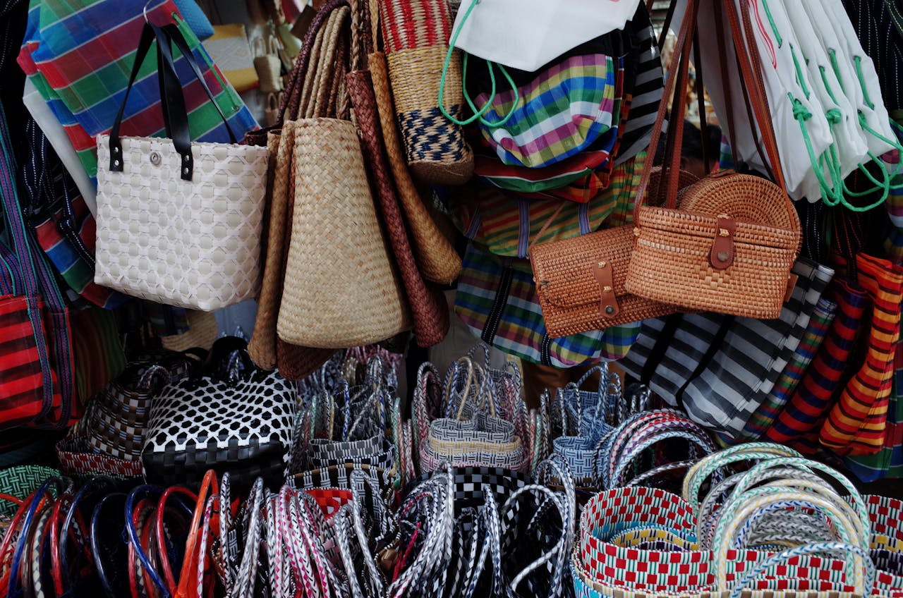 heros-img Vibrant display of handmade woven bags at a street market, perfect for fashion enthusiasts.