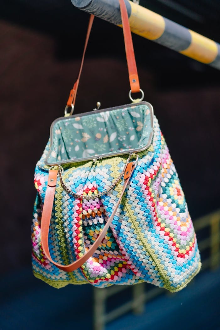 Mastering the First Impression: Your intriguing post title goes here Vibrant multicolored crochet handbag with leather straps hanging on a bar.